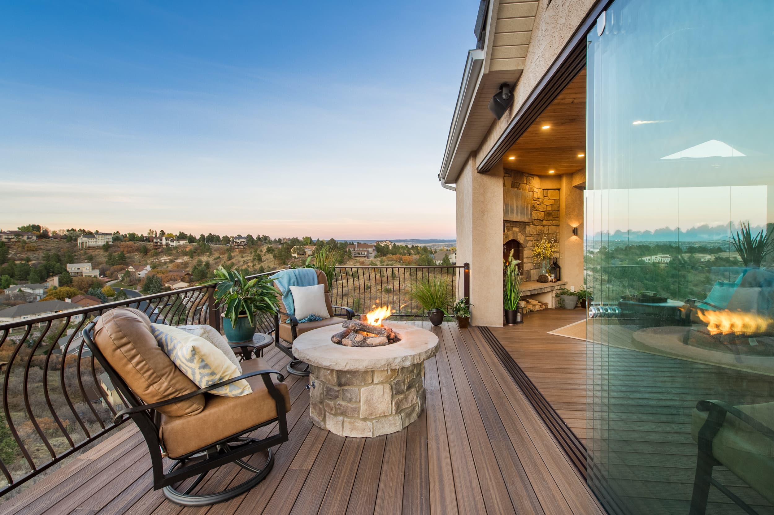 A deck with a fire pit overlooking a city.