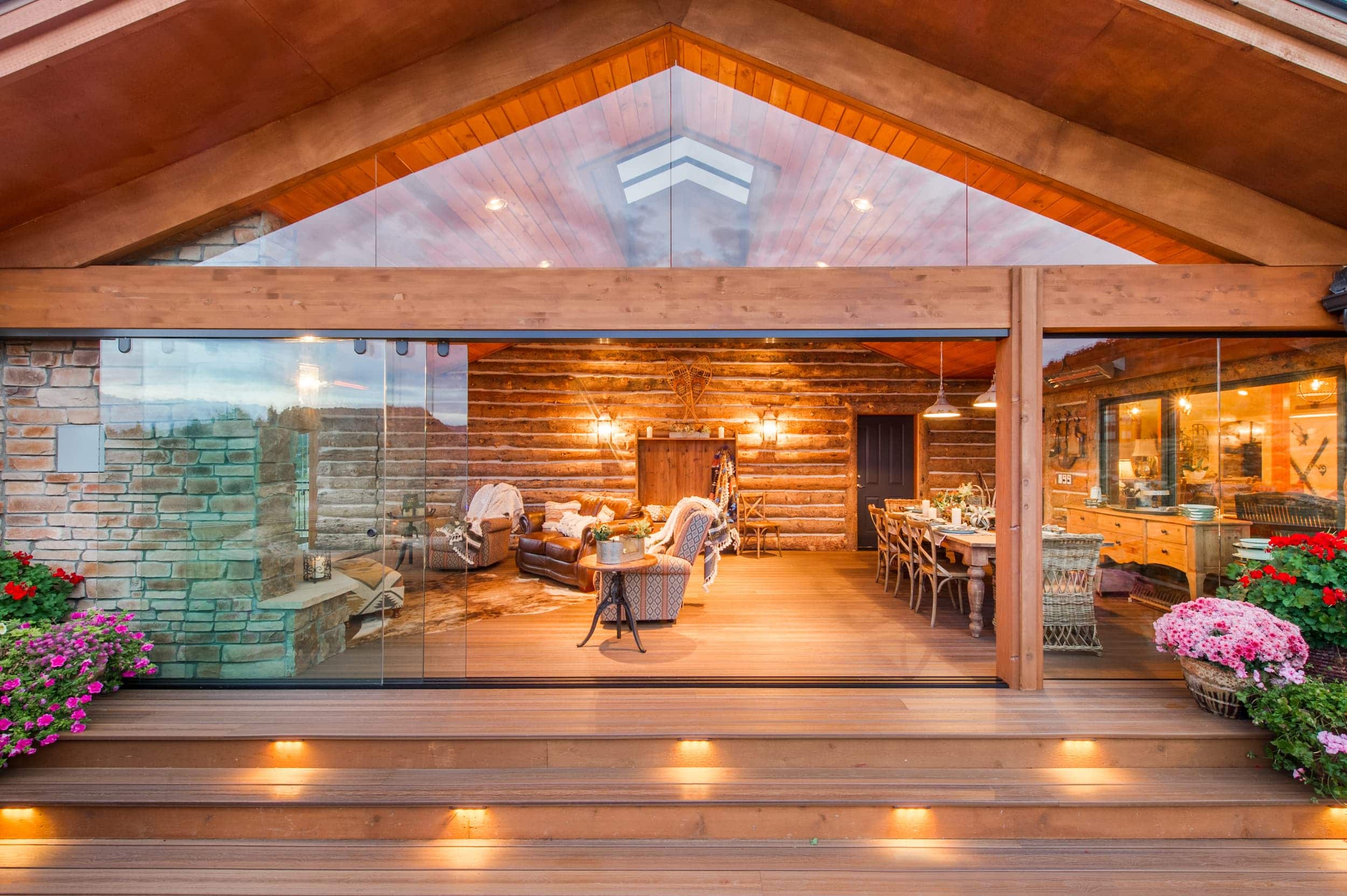 A log home with glass doors and a wooden deck.