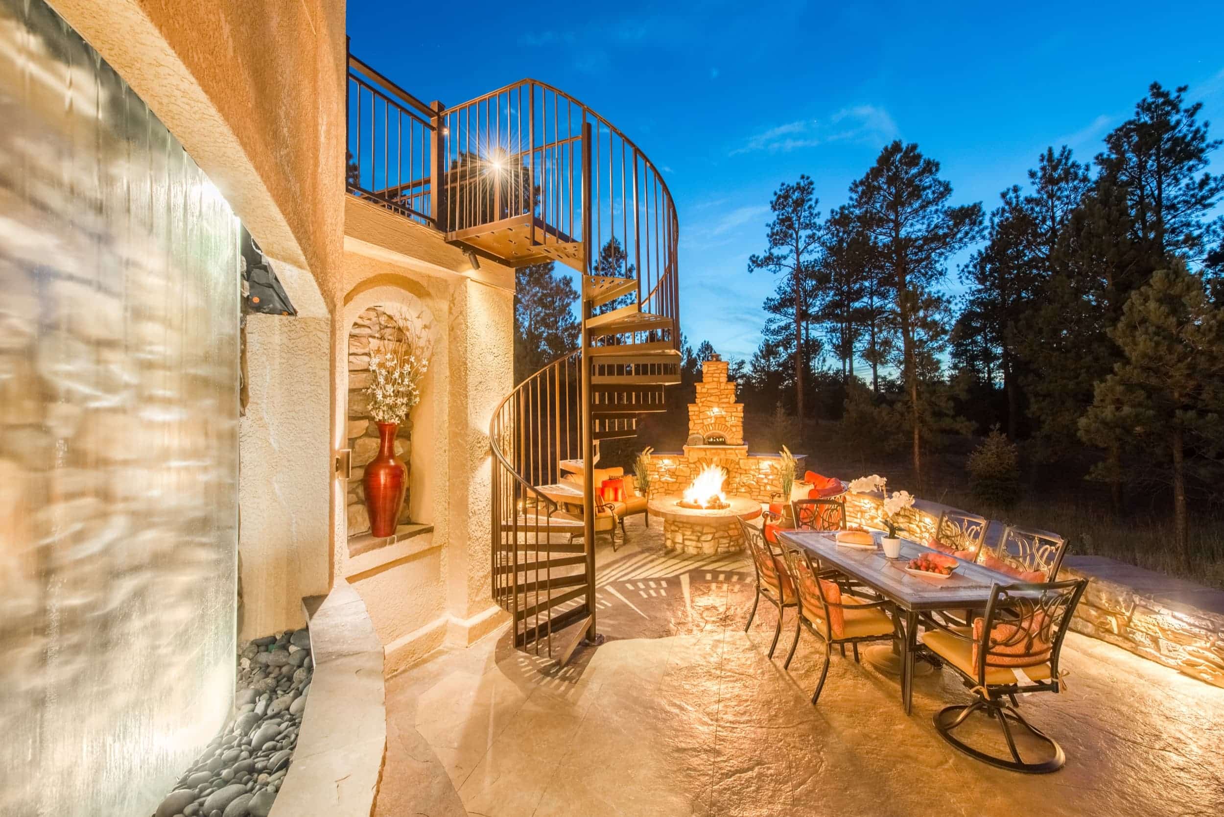 An outdoor dining area with a fire pit and waterfall.