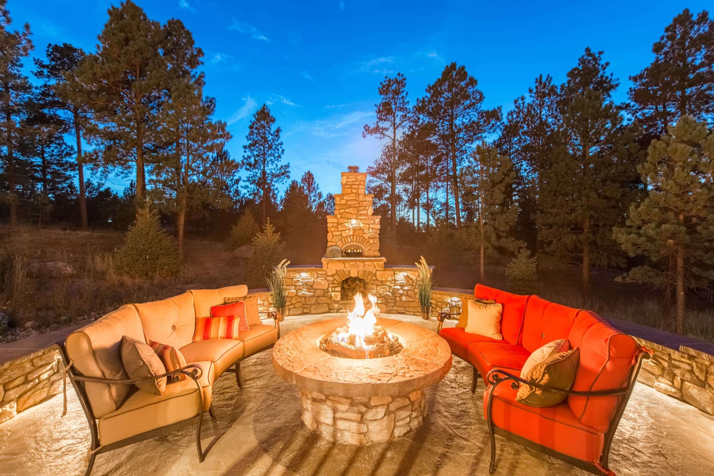 A fire pit in the middle of a patio at dusk.