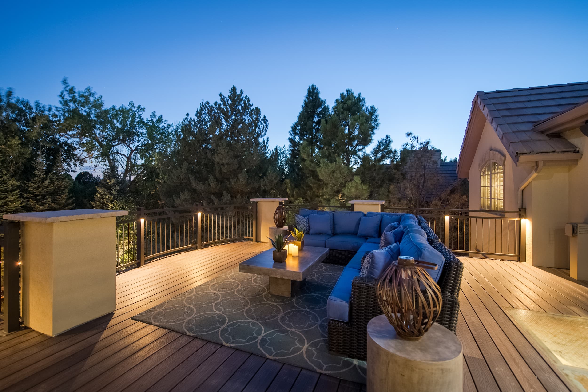 A deck with furniture and lighting at dusk.