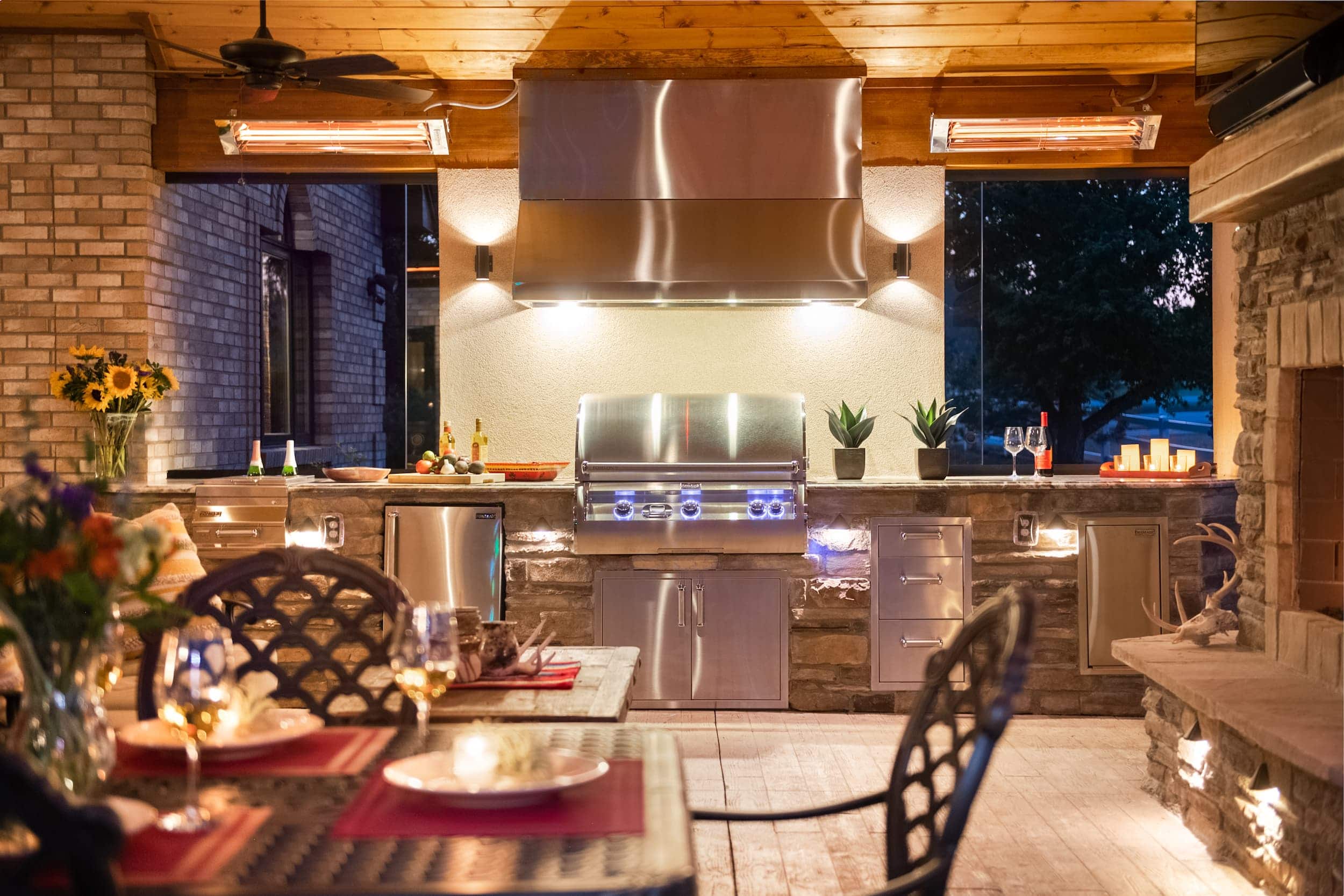 An outdoor kitchen with a fireplace and dining table.